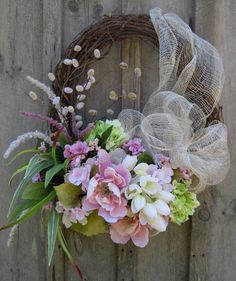 a wreath with flowers is hanging on a fence