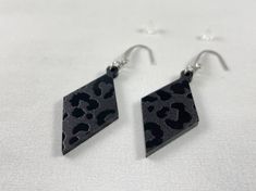 These acrylic diamond shaped leopard print black on black dangle earrings feature stainless steel ear wires with teardrop accent. Lightweight and comfortable with silicone earring backs. These fun laser cut earrings are a perfect gift for Mothers' Day, Birthdays or any special occasion. Please keep in mind that each piece will vary slightly due to the variations of the acrylic material and the handmade nature of the product. The drop length is approximately 2.5” from top of ear wire to bottom of Black Dangle Earrings, Black Earrings Dangle, Laser Cut Earrings, Cut Earrings, Black On Black, Diamond Shaped, Acrylic Earrings, Acrylic Material, Earring Backs