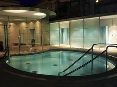 an indoor swimming pool in the middle of a building with glass walls and steps leading up to it