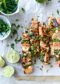 chicken skewers with cilantro and limes on a sheet of paper