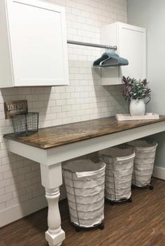 a laundry room with three trash cans under the counter