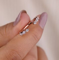 a woman's hand holding a gold ring with three diamond stones on the band