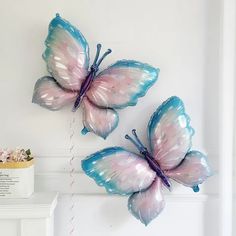 two blue and pink butterflies hanging on the wall