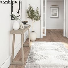 a hallway with white walls and wood flooring has a rug on the floor next to it