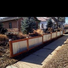 a wooden fence with metal slats on the top and bottom is in front of a house