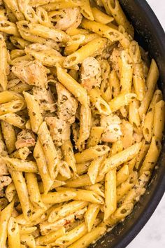 pasta with chicken and sauce in a skillet on a white table top, ready to be eaten