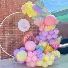 a bunch of balloons that are sitting on the ground in front of a brick wall