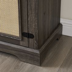 a wooden cabinet sitting on top of a hard wood floor next to a white wall