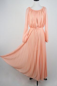 "1970s maxi dress. Peach colored light weight sheer polyester fabric on the outside and lined with an opaque nylon fabric. Long sleeves are unlined and are open from the shoulder to about the elbow with elastic at the wrists. Blousy top, elastic waist, and accordion pleated skirt. There is not a lot of stretch to the waist. Skinny fabric cord belt. Fastens down the back with a metal zipper. Only labels are a size 11/12, ILGWU, and dry clean only. Freshly laundered. (I have to laugh when polyeste Peach Flowy Maxi Dress For Party, Flowy Peach Maxi Dress For Party, Vintage Chiffon Maxi Dress For Spring, 1970s Style Maxi Dress For Summer Evening, 1970s Style Summer Evening Maxi Dress, 1970s Style Spring Evening Maxi Dress, 1970s Style Long Sleeve Maxi Dress For Summer, Peach Floor-length Maxi Dress For Spring, Spring Peach Floor-length Maxi Dress