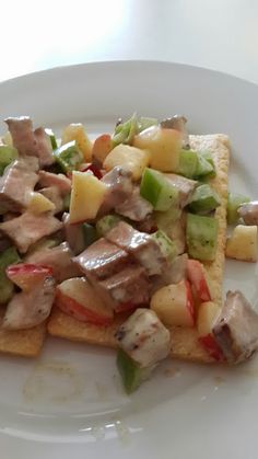 a white plate topped with meat and veggies on top of toasted bread