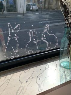 the window is decorated with drawings of rabbits and flowers in vases on the windowsill