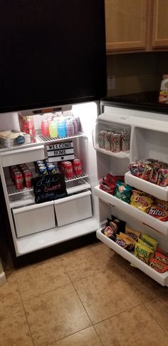 an open refrigerator filled with lots of food and drink items, including sodas and candy bars