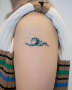 a person with a tattoo on their arm and behind her head is a small wave