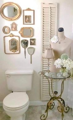 a white toilet sitting in a bathroom next to a table with flowers on top of it