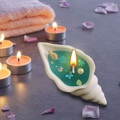 some candles are sitting on a table with towels and petals around the candle holders in front of them