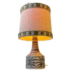 a table lamp with a fabric shade on it's base and an orange light in the middle