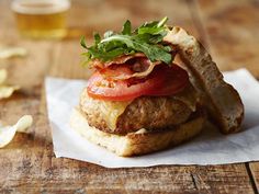 a sandwich with meat, tomato and lettuce on it sitting on top of a piece of paper