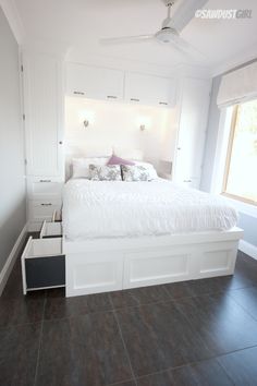 a white bed sitting in a bedroom next to a window