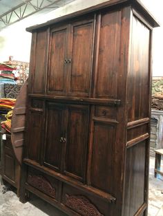 an old wooden armoire sitting on display in a room with other furniture and accessories