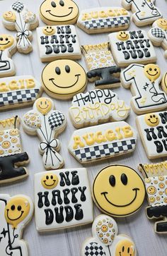 decorated cookies with happy birthday messages and smiley faces are on a white tablecloth covered table