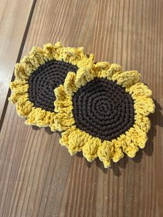 two crocheted sunflowers sitting on top of a wooden table