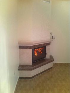 an empty room with a fireplace in the middle and tile flooring on the other side