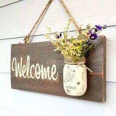 a mason jar filled with flowers hanging from a sign