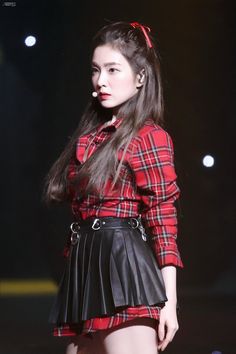 a woman in a red shirt and black leather skirt is standing on the catwalk