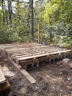 a wooden deck in the middle of a forest with lots of dirt and trees around it