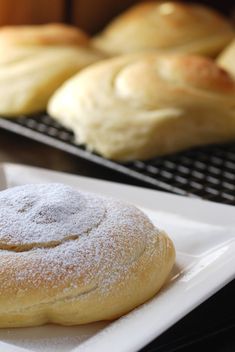 some breads and rolls are sitting on a plate next to each other with powdered sugar on them