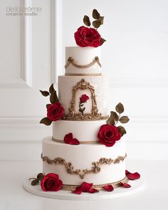 a three tiered wedding cake with red roses on the bottom and gold trimmings