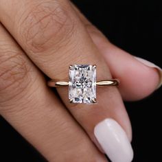 a woman's hand with a gold ring and a diamond engagement ring on her finger