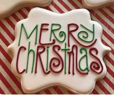 merry christmas cookies with green and red icing on striped tableclothed paper behind them