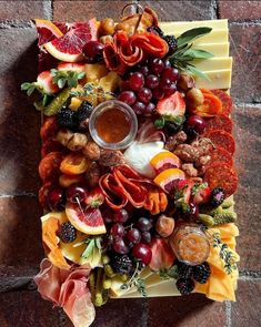 a platter filled with fruit and cheese on top of a brick floor