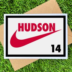 a card with the word hudson on it and a red nike logo in front of some green grass