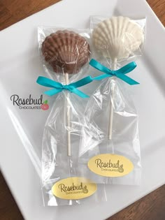 two seashell lollipops wrapped in cellophane on a white plate