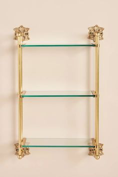 three glass shelves with gold handles on each shelf, one is empty and the other two are closed