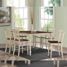 a dining room table with chairs and a vase on the floor in front of it