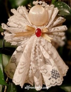 an ornament is hanging from a christmas tree with lace and pearls on it