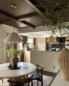 a table with chairs and a vase on it next to a kitchen area that has an island in the middle