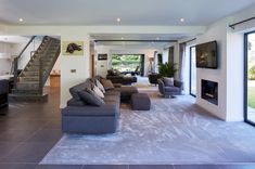 a living room filled with lots of furniture and a staircase leading up to the second floor