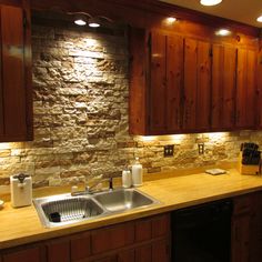 a kitchen with wooden cabinets and stone backsplashing on the wall above the sink