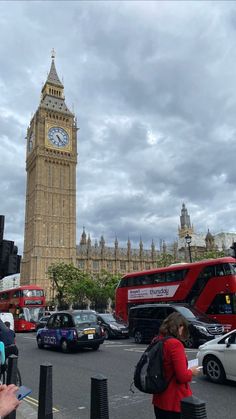 the big ben clock tower towering over the city of london as traffic passes by on a cloudy day