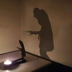 a shadow of a person standing in front of a table with a light on it