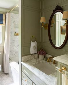 a bathroom with green walls and marble counter tops, along with a large mirror on the wall