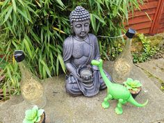 a buddha statue sitting on top of a cement slab next to two small glass vases