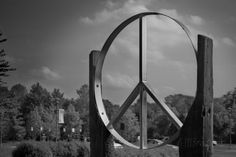 a black and white photo of a peace sign in the middle of a park with trees