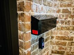 a mailbox mounted to the side of a brick wall next to a red light