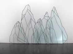 a sculpture made out of glass with mountains in the background