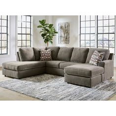 a large sectional couch with pillows on top of it in front of a rug and windows